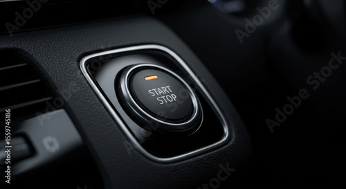 A close up shot of a car's start stop button surrounded by a chrome trim on a dark dashboard