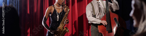 Photography Black young adult woman playing saxophone and Caucasian middle aged man playing