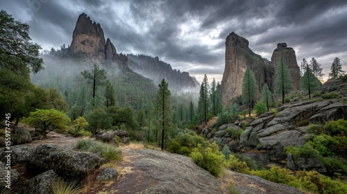 Majestic Mountain Landscape with Tall Rock Formations and Dense Green Forest Under Dramatic Cloudy Sky