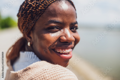 Close up head shot portrait of cheerful young black woman with dental braces.