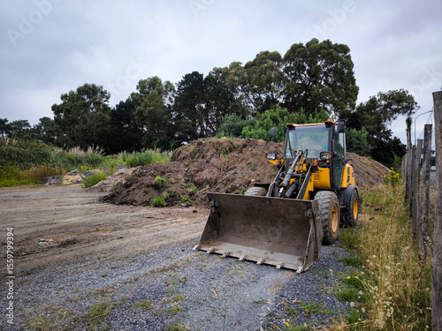 Carregadeira de rodas em ação no espalhamento de terra em meio a uma zona rural para a construção de uma estrada num dia muito nublado