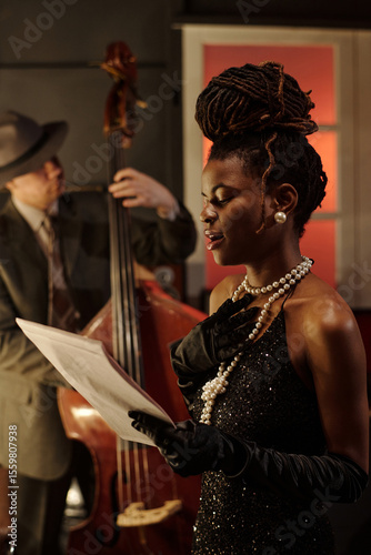 Canvas Print Young Black woman singing while holding sheet music, wearing elegant gloves and
