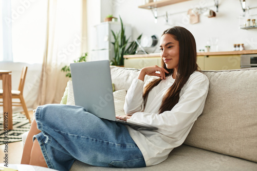 фотографія Charming young woman enjoys a quiet afternoon at home while working on her lapto