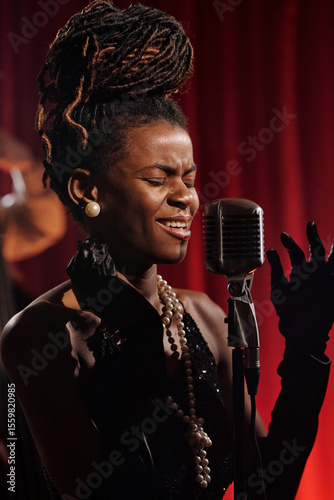 Canvas Print Black young adult woman singing passionately into vintage microphone on stage, e