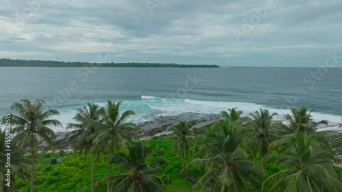 An aerial view of a tropical island with white sand beaches and turquoise waters. Waves crashing on a tropical beach