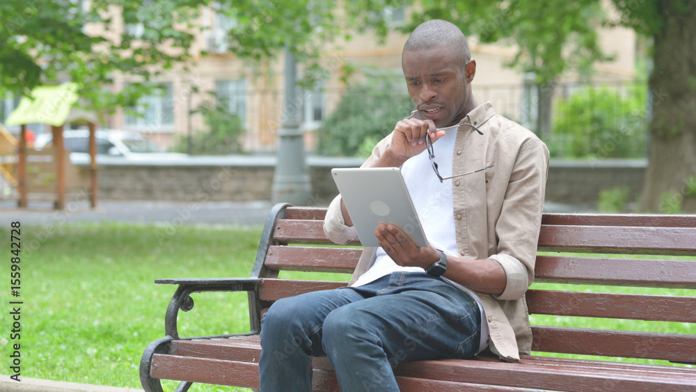 Obraz premium Young African Man Expressing Disbelief While Using a Tablet