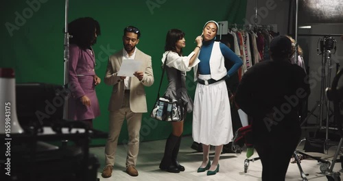 Woman, actress and makeup artist on film set for face, director and cameraman for production. People, cosmetics and touchup with green screen, cinematography or recording equipment at movie studio