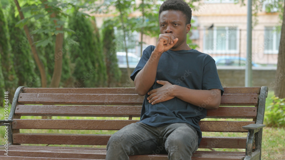 Obraz premium Sick Casual African Man Coughing on a Park Bench
