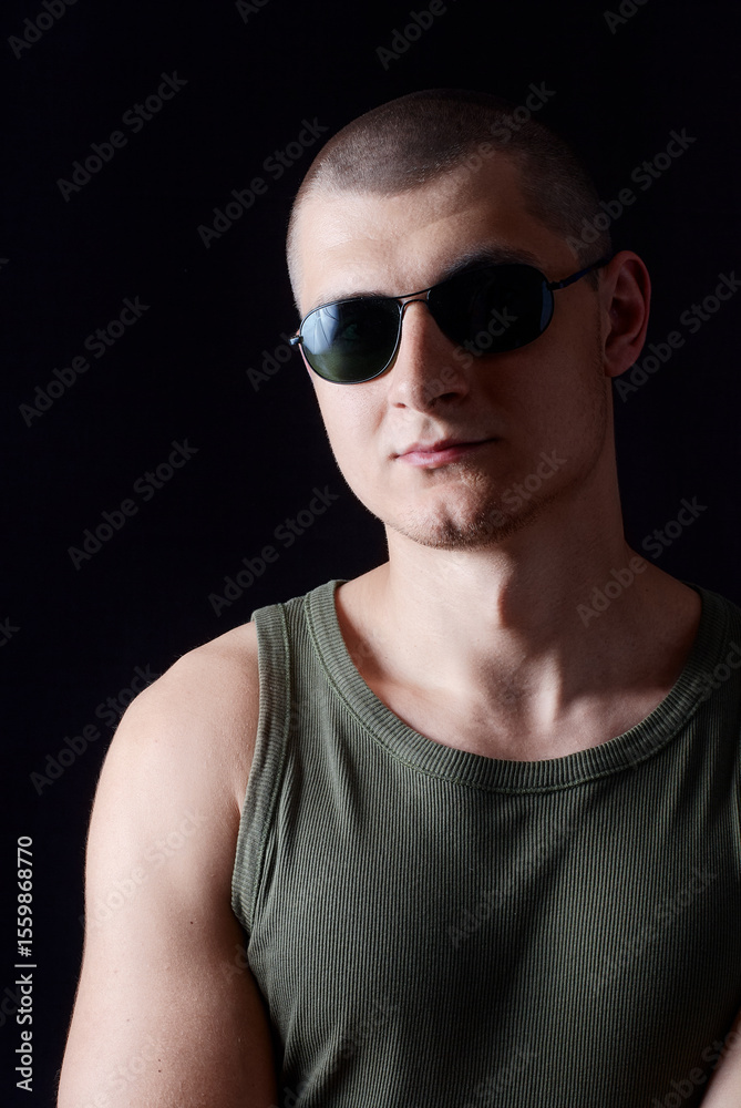 Naklejka premium Portrait of a Confident Man Wearing Sunglasses in a Dark Setting