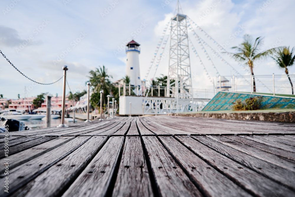 Fototapeta premium Wooden Boardwalk Leading to Lighthouse and Palm Trees in Tropical Marina