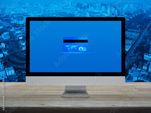 Fototapeta Naklejka Na Ścianę i Meble -  Credit card on modern computer monitor screen on wooden table over city tower, street, expressway and skyscraper, Online e-payment concept, Elements of this image furnished by NASA