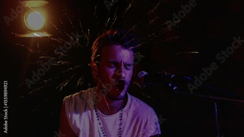 Drummer intensifying strikes drum kit under spotlight activating fireworks behind head for climax