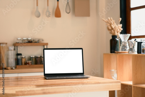 Laptop with blank screen on a wooden kitchen counter.