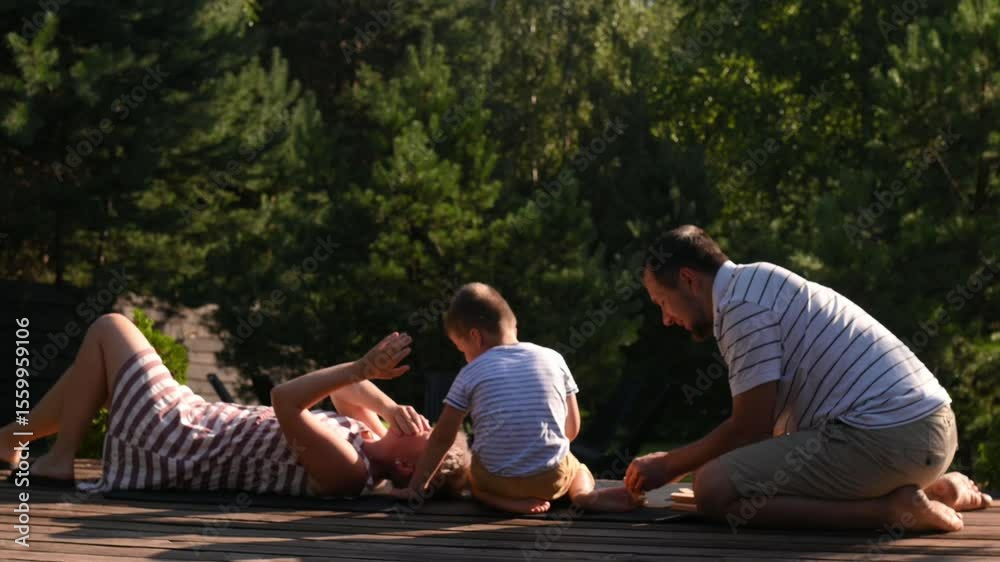 Mom, dad and son play jenga on the terrace in the summer sun street. Family vacation, child development. Game competition
