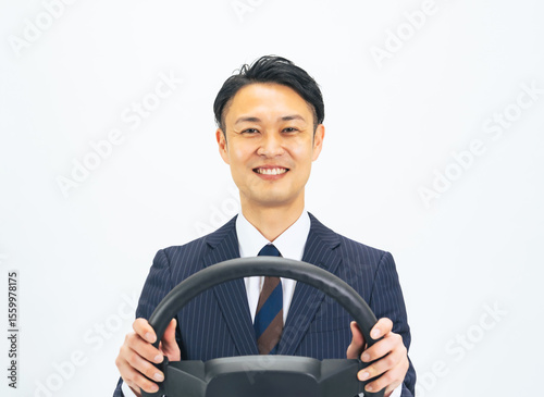 ハンドルを持って笑顔で運転するミドルエイジ男性ビジネスパーソン