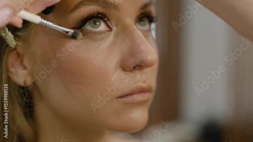 Under eye circle corrector, foundation. Makeup artist applies under eye circle corrector cream to model face. Close-up