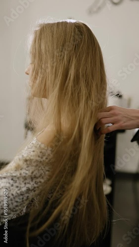 Hair drying. Hairdresser stylist make-up artist dries blows hair dryer long women hair. Vertical video