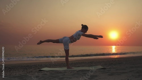 Woman Practicing Warrior III Yoga Pose at Sunset on the Beach