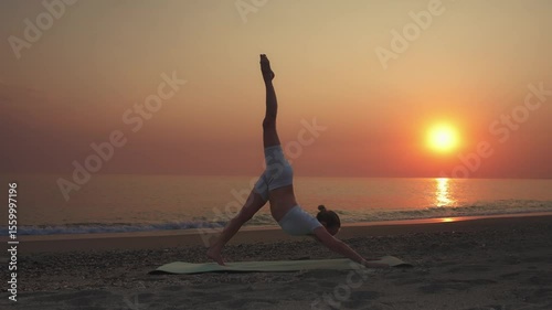 Woman Practicing Three-Legged Downward Dog Yoga Pose at Sunset on Beach