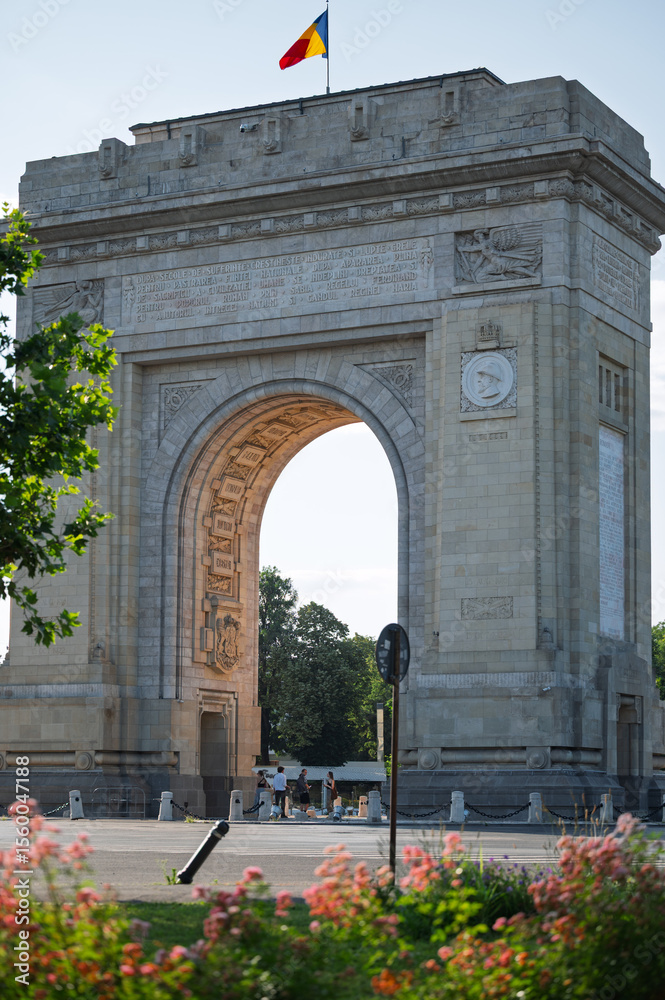 Obraz premium The famous triumphal arch monument in Bucharest, Romania, a popular European travel destination and symbol of history and victory, on a clear summer day.