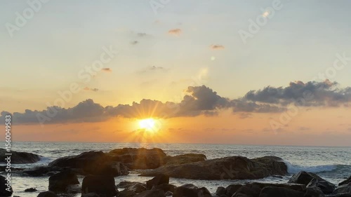 Captivating image of a golden sunset peeking over ocean waves, captured at sea level. The sun's rays create a serene and peaceful atmosphere over the calm water surface.