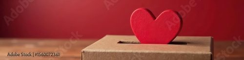 Red heart gently placed in donation box Valentine's Day charitable giving , romance, benevolence