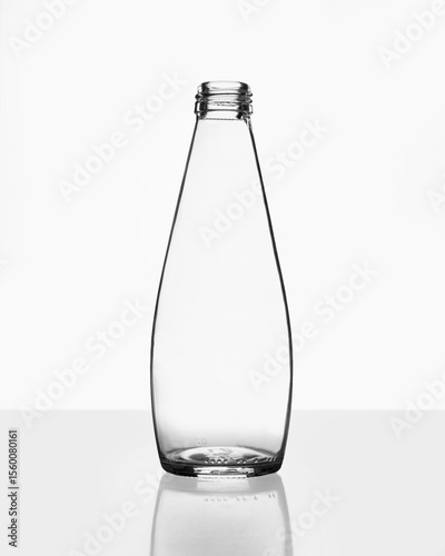 4K clear tapered conical glass bottle with subtle mid-section expansion on reflective white surface, studio-lit commercial mockup for liquid or juice packaging