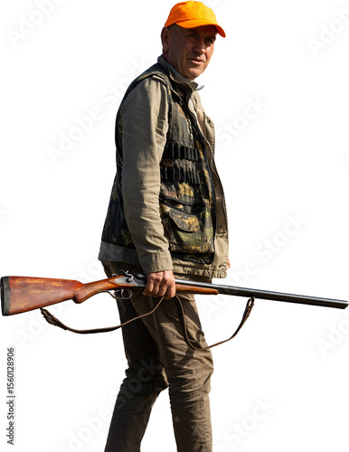 Mature man hunter with gun while walking on field.