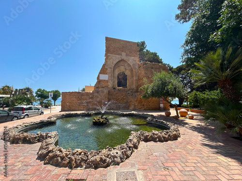 Castellammare del Golfo in Sicily, Italy. The characteristic old stone buildings, archway, and palm trees match the landscape of Castellammare del Golfo.