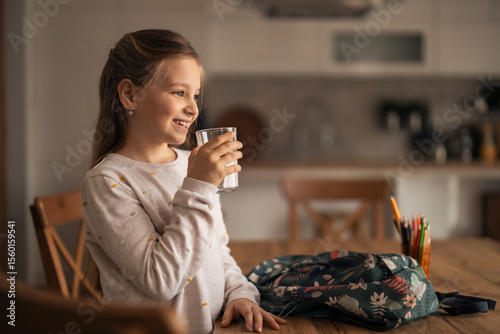 Young Girl Drinking Water with a Backpack Nearby