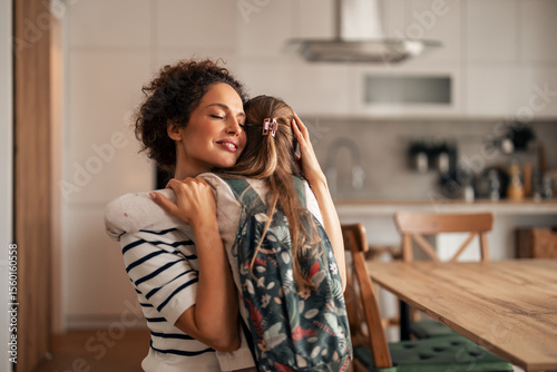 Mother Hugging Daughter with Backpack in Kitchen, Warm and Loving Scene