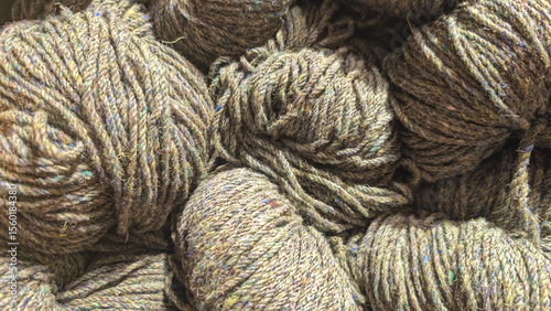 Wool bundles of soft green yarn are displayed closely together, showcasing their texture and color, inviting crafters to explore unique projects in a vibrant marketplace atmosphere. Wool background