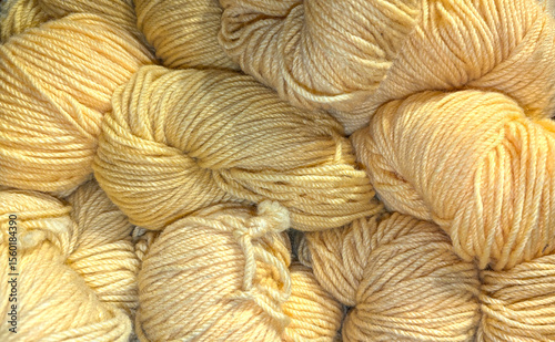 Wool bundles of yellow yarn are displayed closely together, showcasing their texture and color, inviting crafters to explore unique projects in a vibrant marketplace atmosphere. Wool background