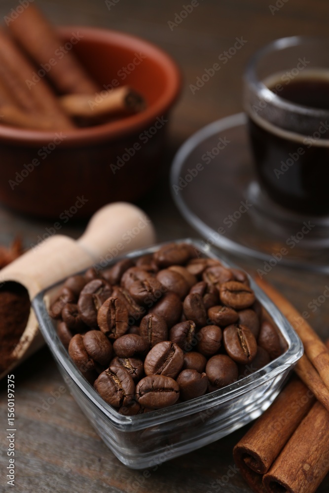 Roasted beans, scoop and cinnamon sticks on wooden table, closeup Roasted beans, scoop and cinnamon sticks on wooden table, closeup