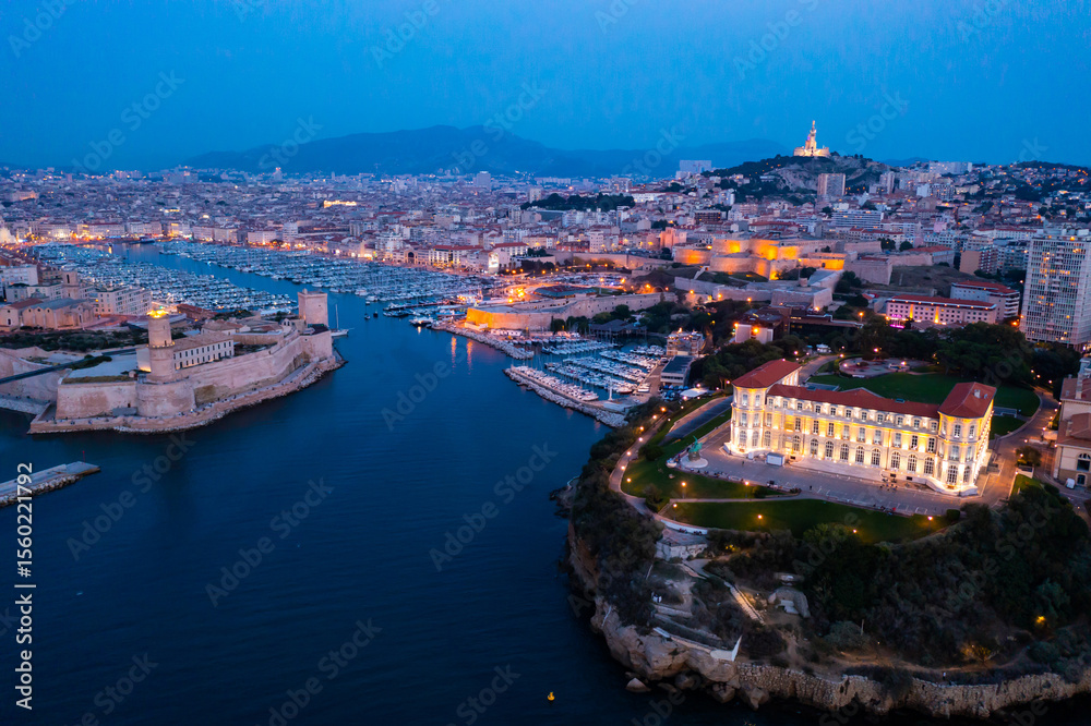 Fototapeta premium Aerial view of old port, Tour du Fanal and Basilica of Notre Dame at Marseille, France at night