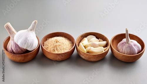quatre bols en bois contenant differentes formes d ail bulbes entiers gousses pelees et morceaux haches