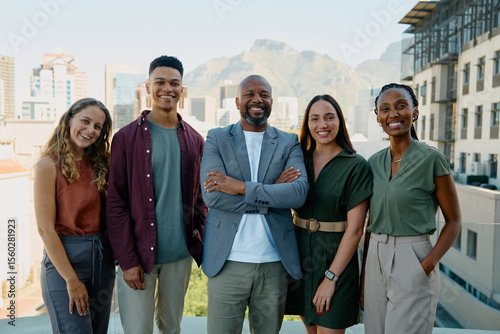 Diverse group of smiling business professionals standing together on rooftop in city on sunny day