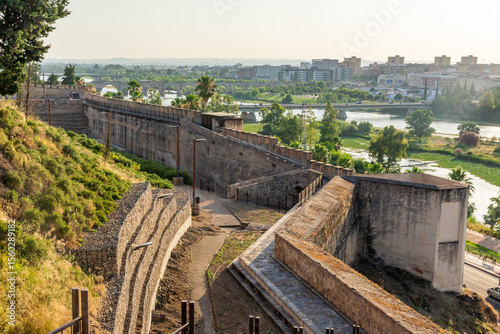 Panoramic sunset view of the longest city walls in Europe in Badajoz, with the Guadiana River and its bridges illuminated by the golden sunset light.