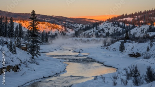 Serene sunrise over tranquil river with mist drifting above majestic mountain summits