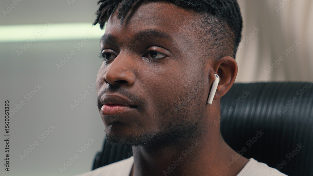 Obraz premium Close up happy smiling African American guy man ethnic male putting wireless headphones in ears listening music enjoying audio song in earphones positive relax in futuristic white studio futurism