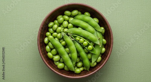 Fresh green peas in brown bowl on textured green background