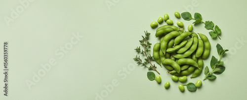 Fresh edamame beans and herbs arranged on a pale green background