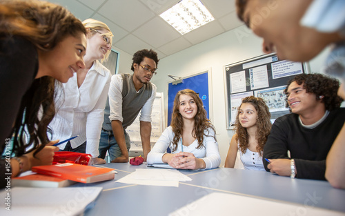 Teenage Students: Group Project. A group of college students working together with their teacher in the classroom. From a series of related images.