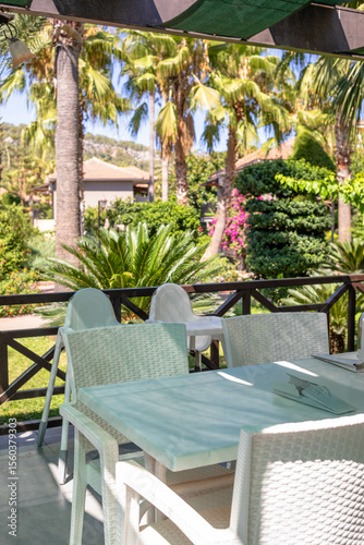 Outdoor dining area with white furniture surrounded by lush greenery and tropical plants