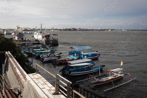 Fototapeta Naklejka Na Ścianę i Meble -  Traditional Indonesian Jukung and Tour Boats in a Bali Harbor