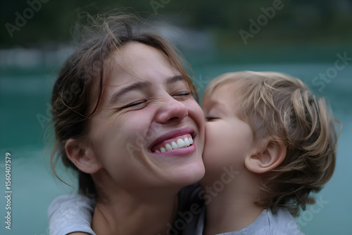 Mother and child candid outdoor hug tender kiss authentic lifestyle happy family bonding emotional parenting moment natural light stock photo