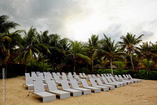Rows of Empty Lounge Chairs on a Beach Front under a Cloudy Sky