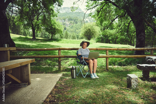 Woman Enjoying Remote Work Outdoors at a Scenic Park with Laptop and Coffee