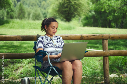 Woman Using Laptop Outdoors in a Scenic Park Setting