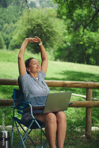 Woman Relaxing While Working on a Laptop Outdoors in a Scenic Park